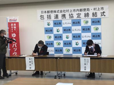 協定書に署名する高橋市長と五十嵐朝日郵便局長