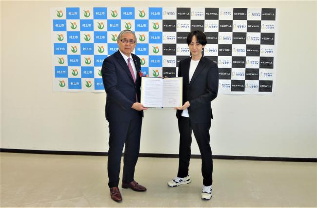 締結した協定書を掲げた写真