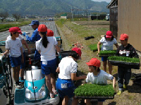 児童が田植え機に苗を運ぶ様子