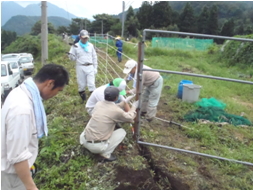 住民が電気柵の電線を張っている風景